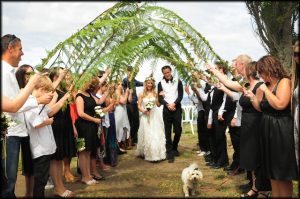 Fern fronds act as an arch to this wedding couple